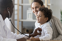 Male doctor treating boy with mother