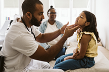 Male doctor treating girl patient